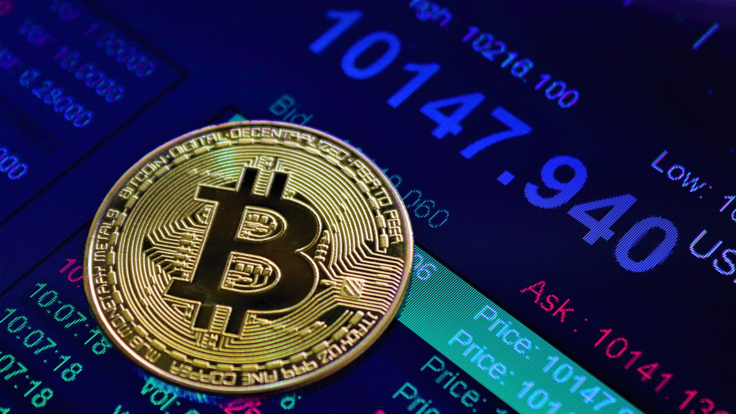 Bitcoin-Münze auf einem Display mit einer Kursanzeige von 100.000 US-Dollar