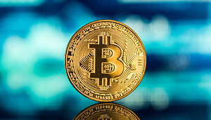 Eine Bitcoin-Münze vor einem Kurschart