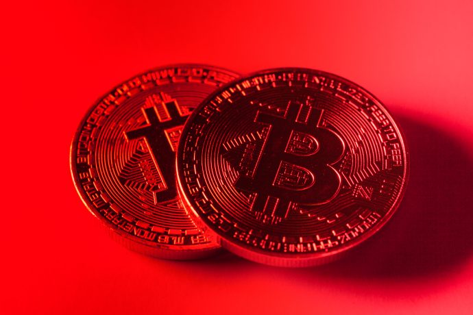 Zwei Bitcoin-Münzen vor rotem Hintergrund