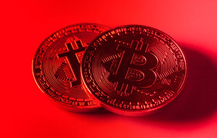 Zwei Bitcoin-Münzen vor rotem Hintergrund