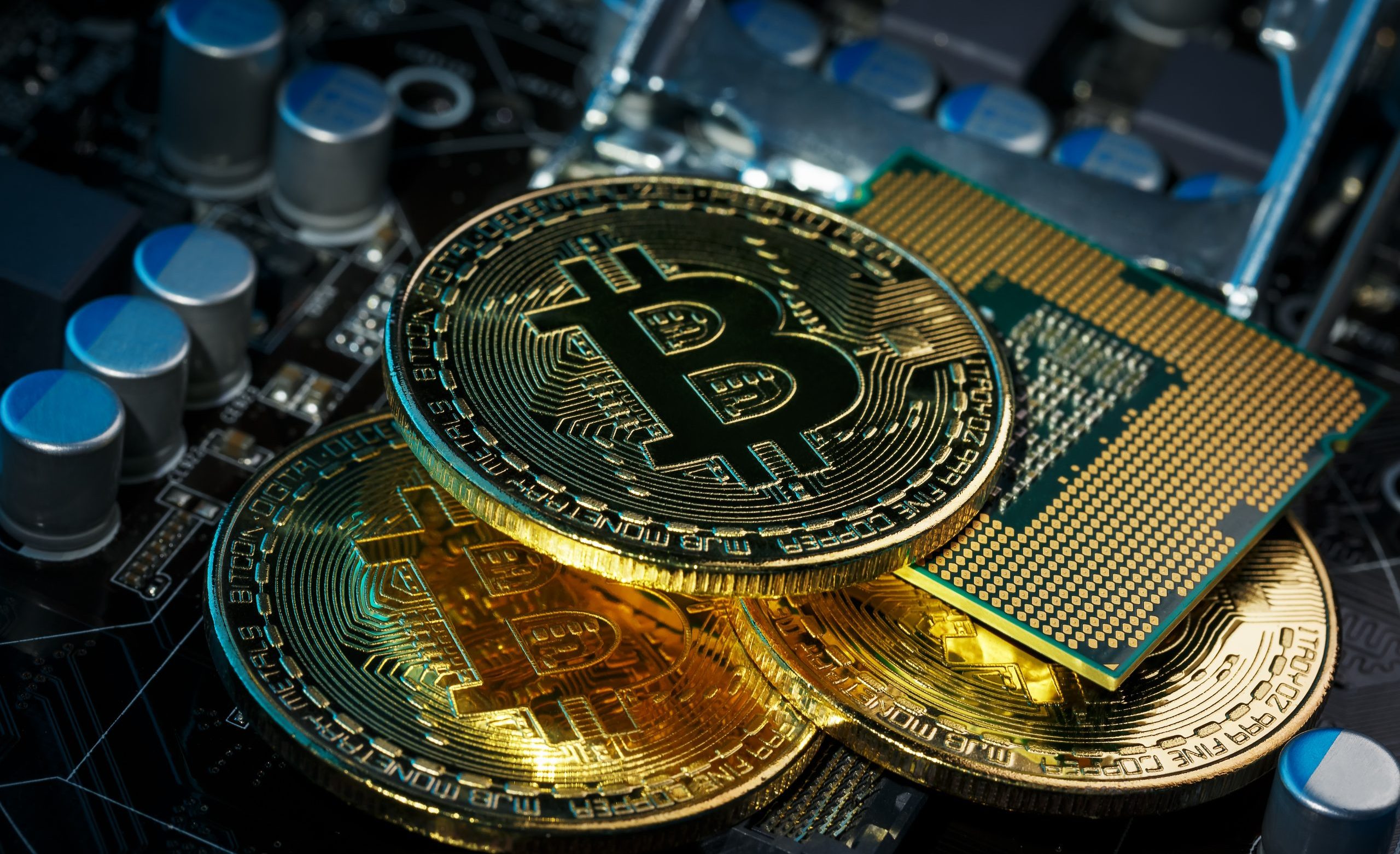 Drei Bitcoin-Münzen liegen auf den Sicherheitselementen einer Hardware Wallet.