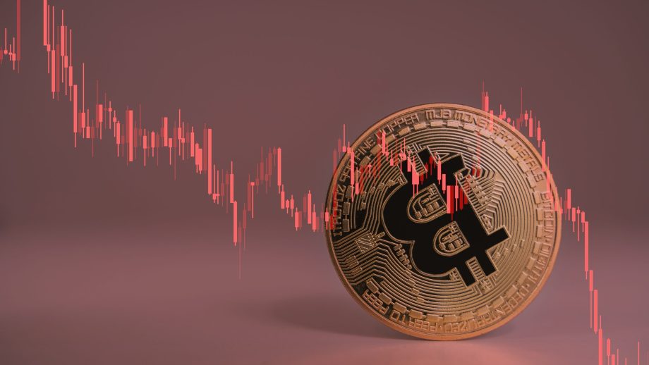 Eine umgekippte Bitcoin-Münze mir rotem Chart symbolisiert den fallenden BTC-Kurs