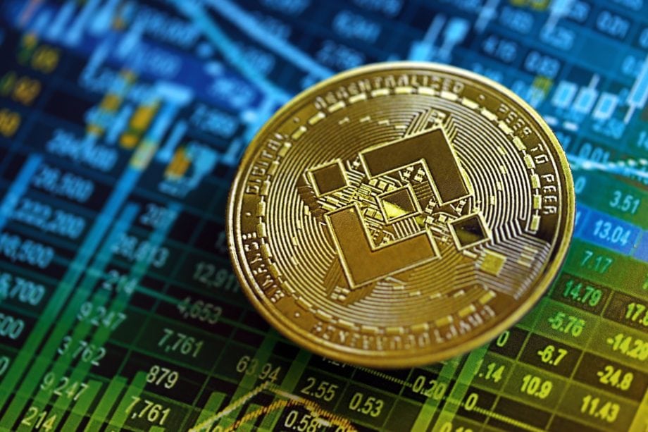 Eine BNB-Münze vor einem blauen Chart als Hintergrund