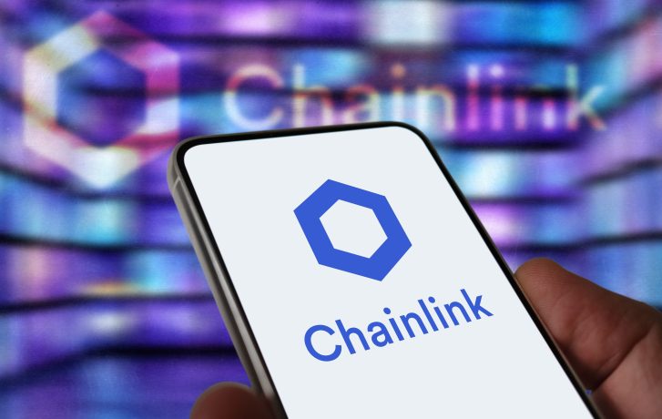 Eine Hand hält ein Smartphone, auf dem das Chainlink-Logo abgebildet ist