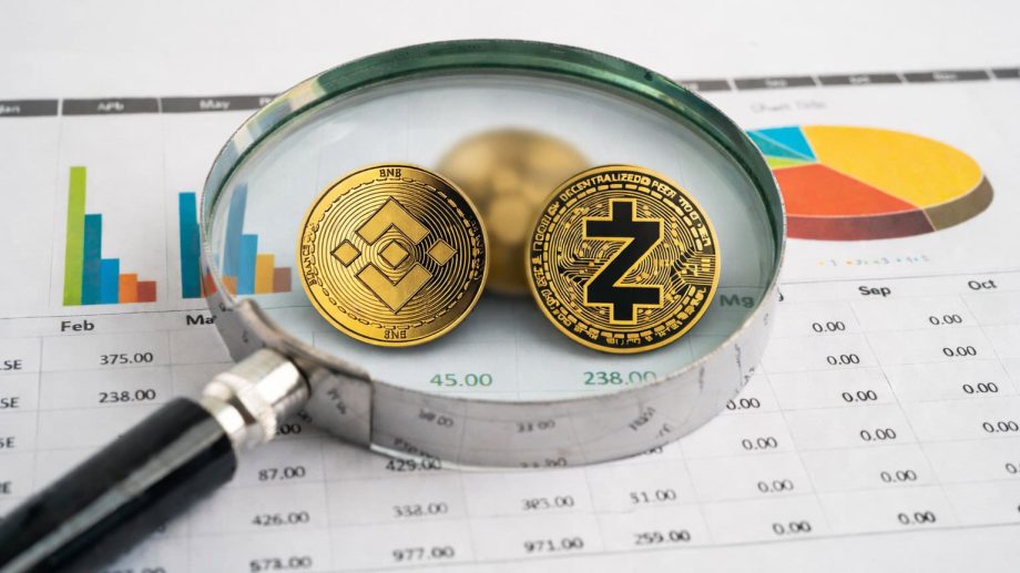 Kryptowährungen unter einer Lupe auf einem Blatt mit Finanzgrafiken