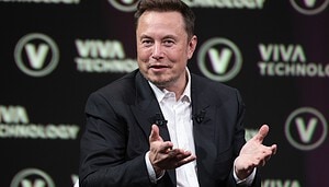 Elon Musk zeigt mit seinen Händen, warum er vielleicht in Bitcoin investieren wird.