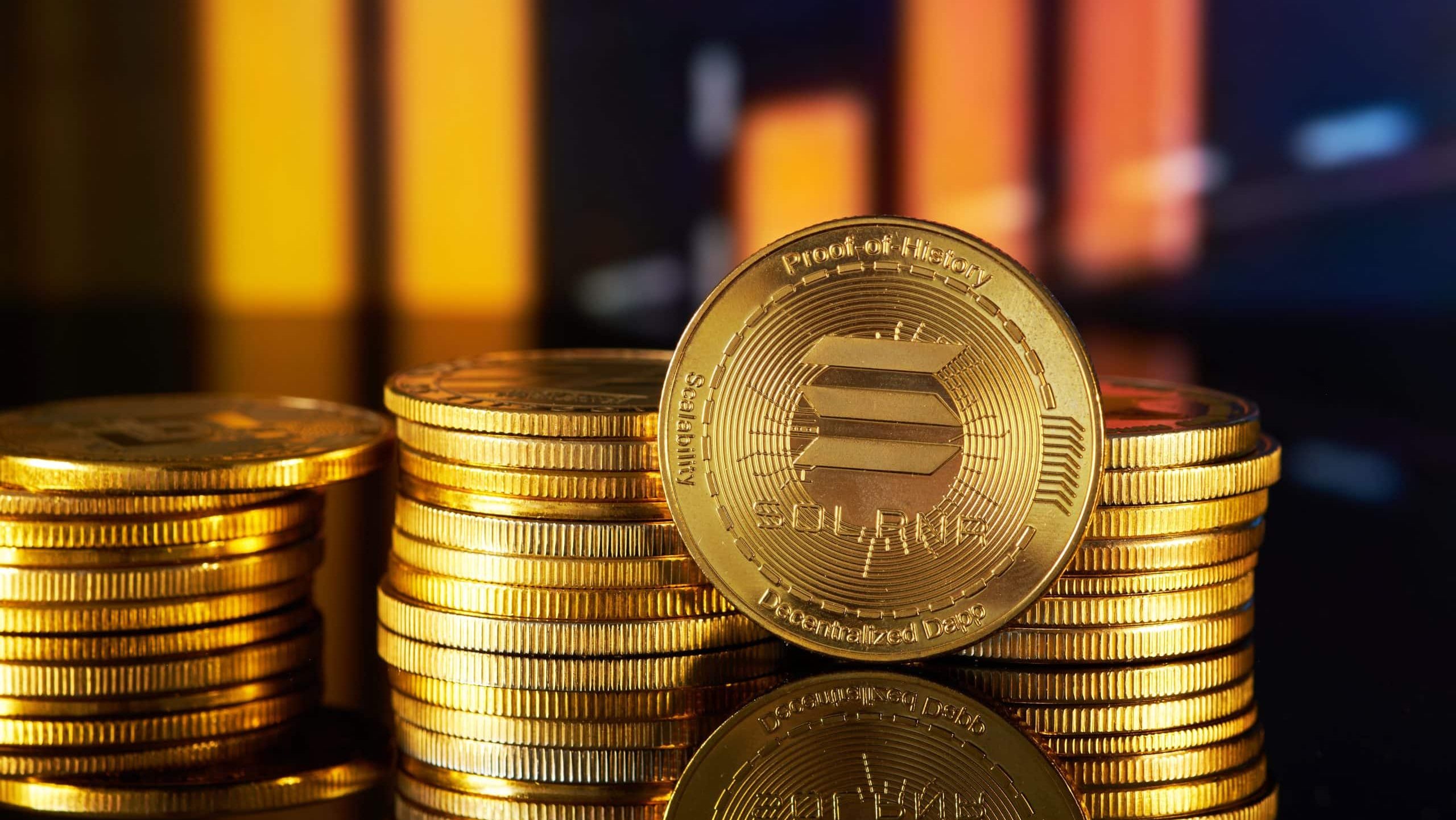 SOL-Coin-Stapel vor einem dunklen Hintergrund mit Kursdiagrammen