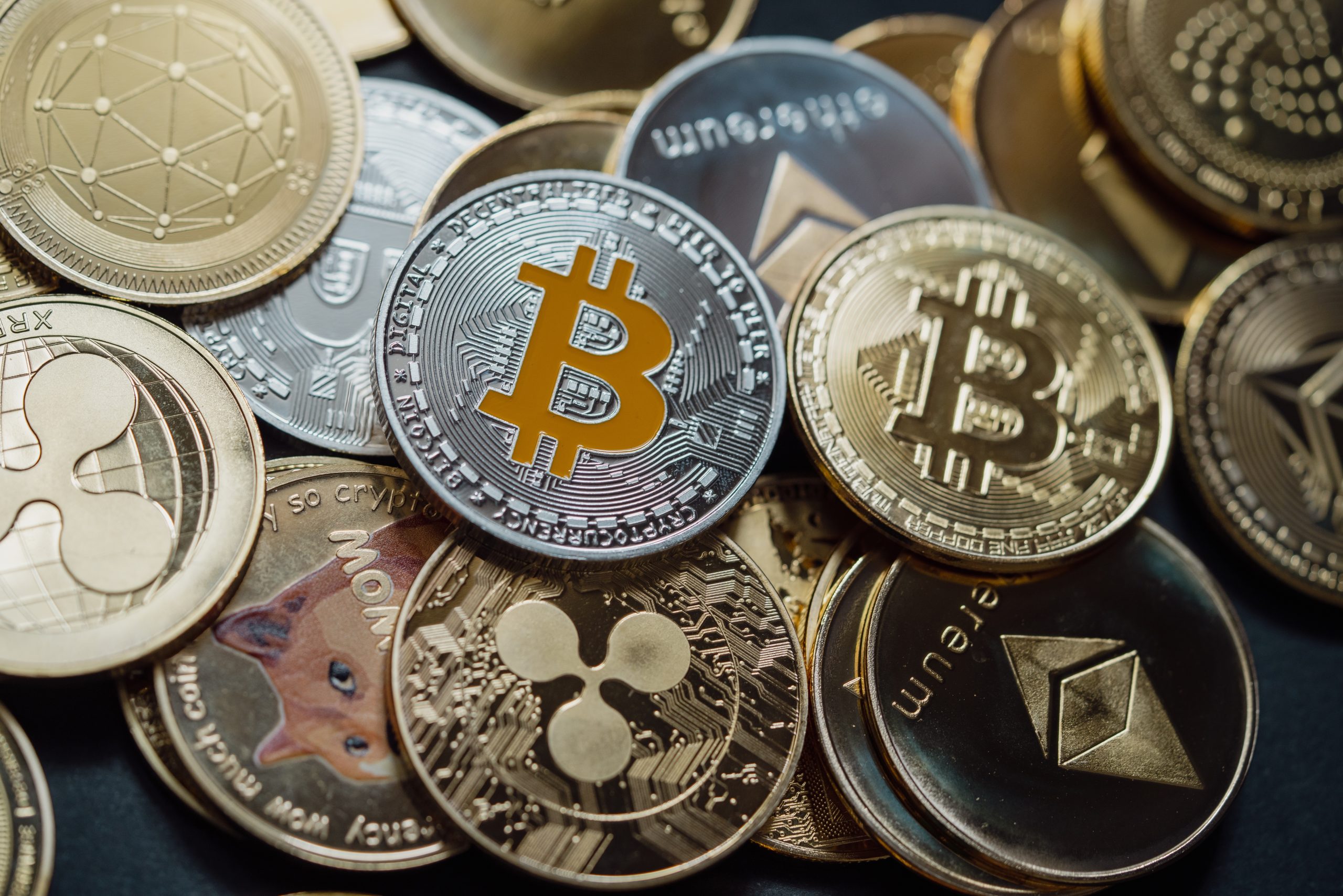 Zu sehen sind verschiedene Münzen von Kryptowährungen wie Bitcoin und Ethereum, die auf einem Haufen liegen