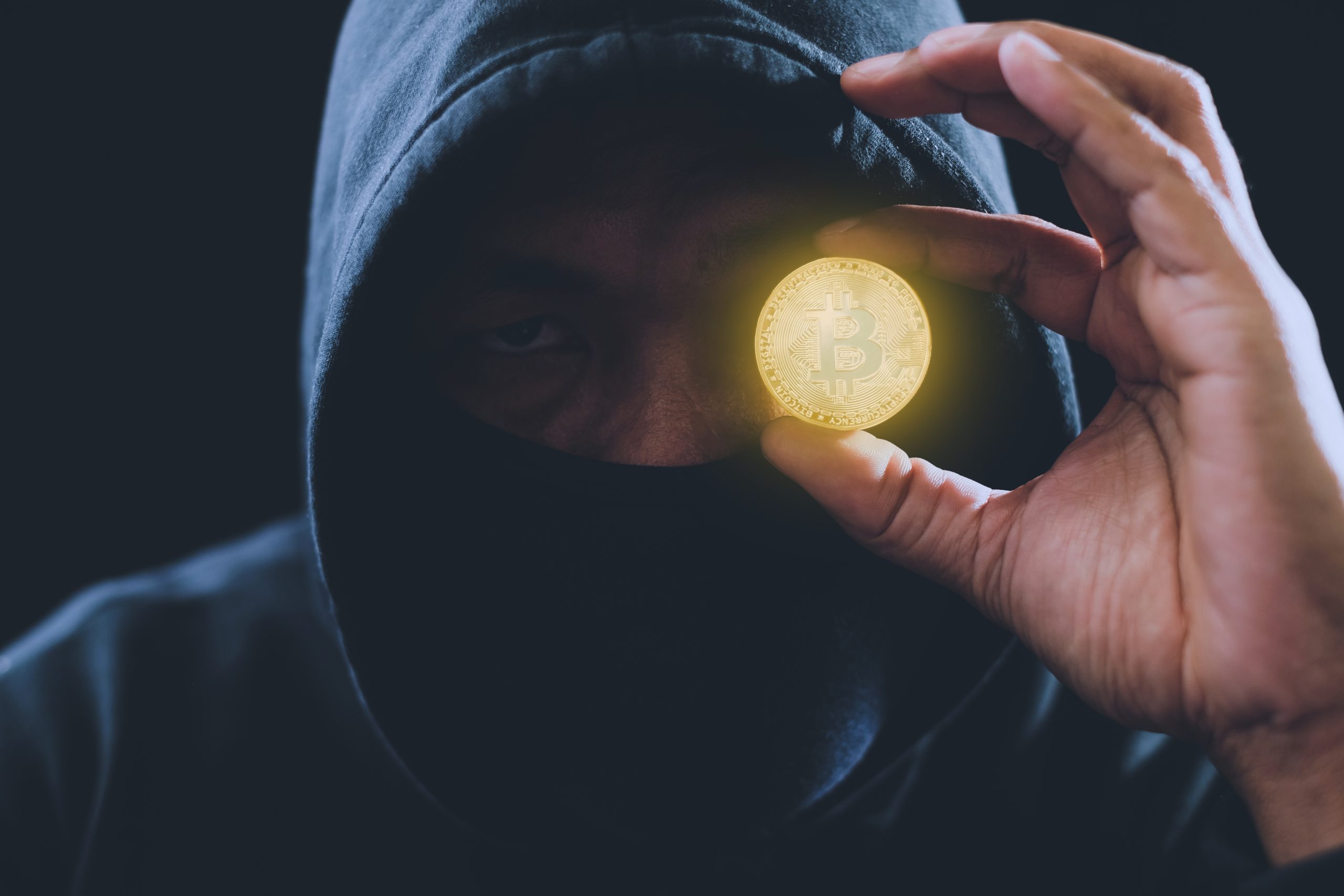 Krimineller hält Bitcoin-Münze hoch