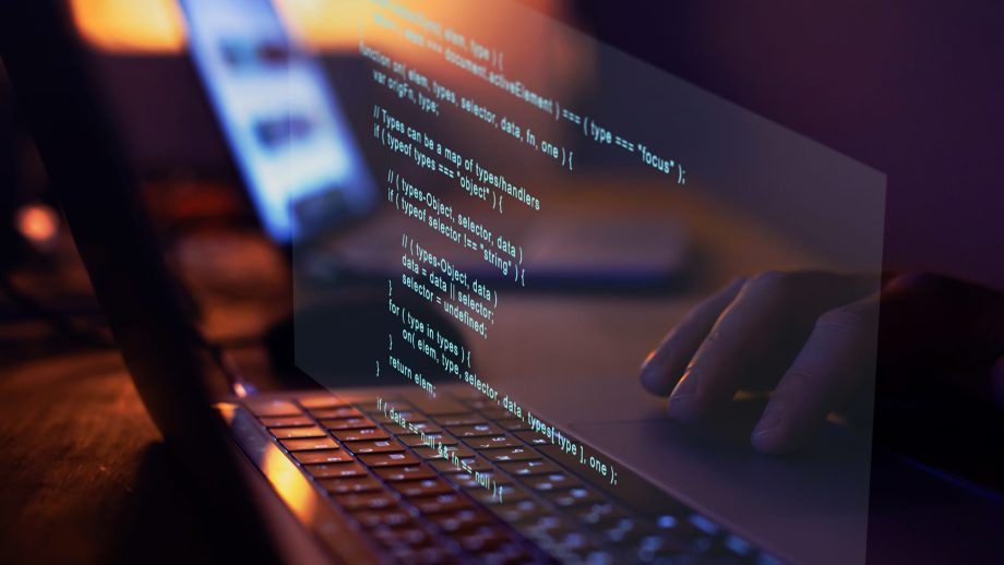 Laptop-Spiegelung mit Code-Zeilen auf einem Schreibtsich