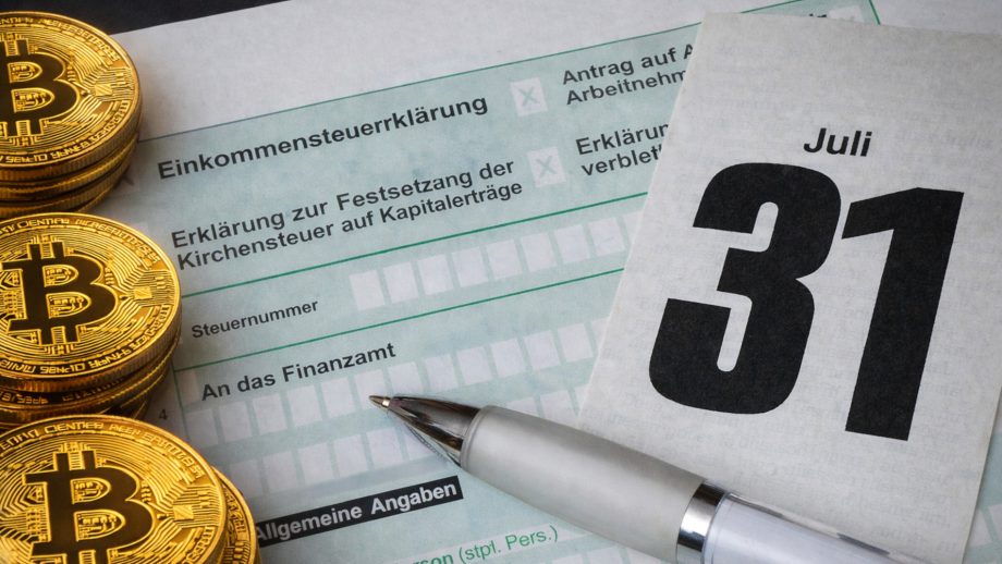 Bitcoin-Münzen (links) liegen auf einer Steuererklärung, dazu ein Kugelschreiber und ein Kalender mit dem Abgabedatum 31. Juli (rechts)