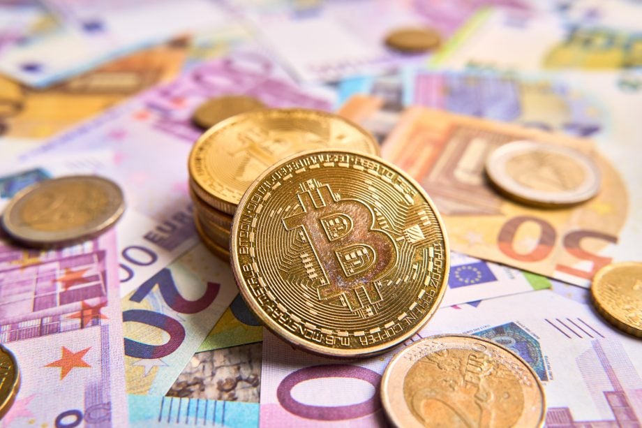 Die Grafik zeigt Bitcoin-Münzen auf Geldscheinen