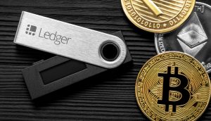 Ledger Hardware-Wallet iegt auf Tisch neben Krypto-Münzen
