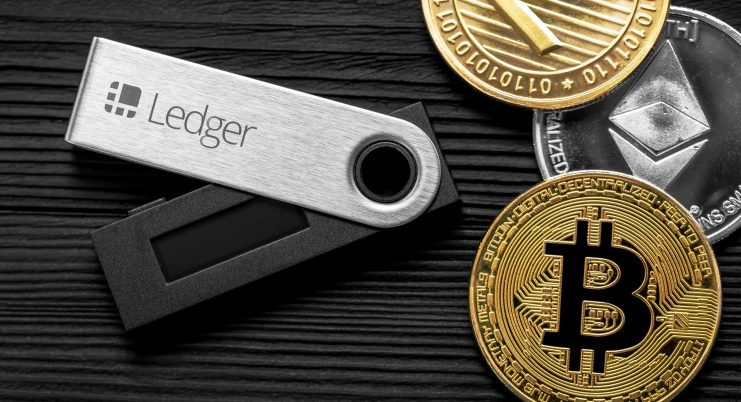 Ledger Hardware-Wallet iegt auf Tisch neben Krypto-Münzen