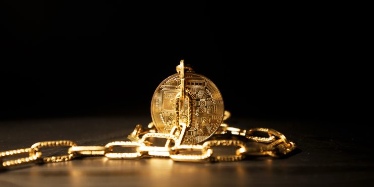 Eine goldene Münze gesichert durch eine schwere Kette, auf dunklem Hintegrund