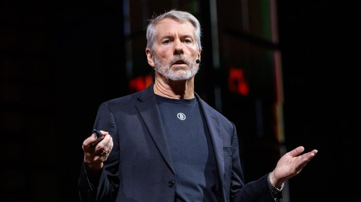 Michael Saylor steht auf einer Bühne im dunklen Anzug und spricht über Bitcoin