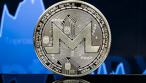Eine Symbolmünze der Kryptowährung Monero vor einem blau gefärbten Kurschart