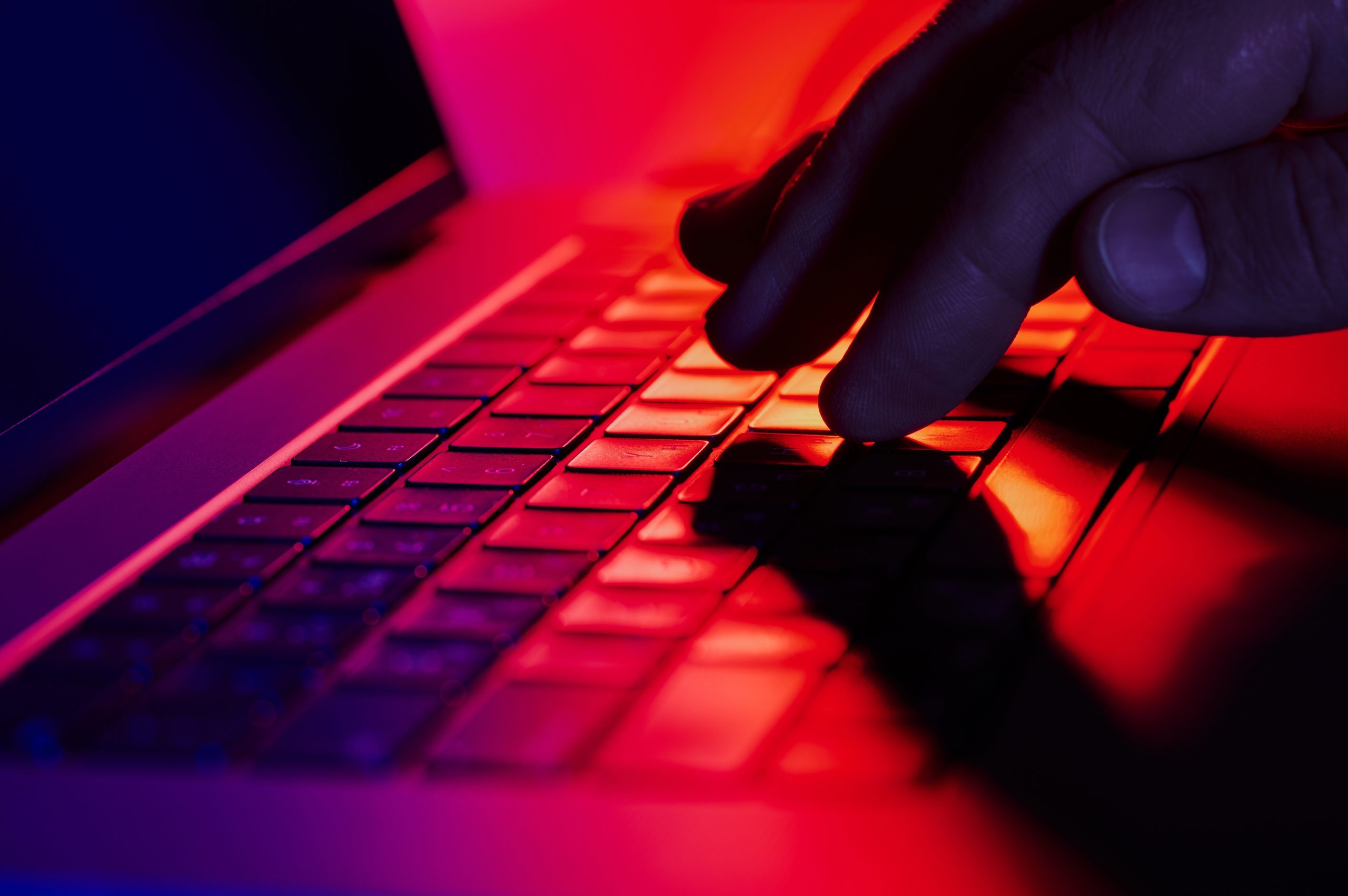 Eine Hand auf einem Laptop vor einem roten Hintegrund