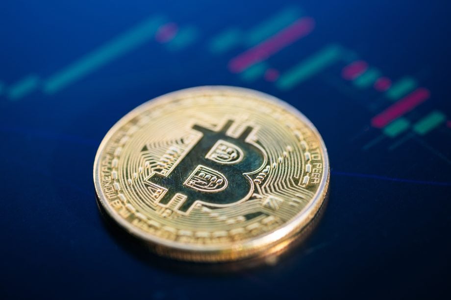Eine Bitcoin-Münze vor einem Charthintergrund