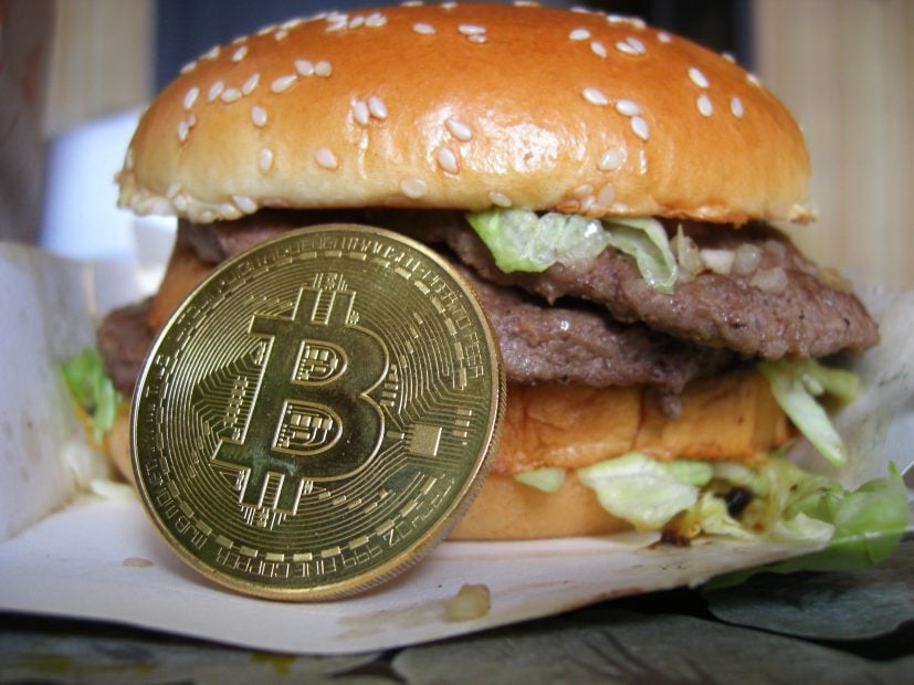 Das Bild zeigt einen Burger und eine Bitcoin-Münze