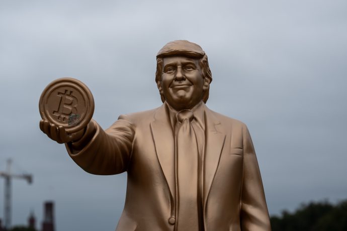 Eine Statue von Donald Trump, die eine Bitcoin-Münze hält.