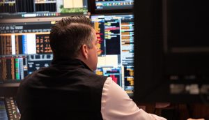 Ein Trader sitzt vor einem Bildschirm mit Finanzdaten