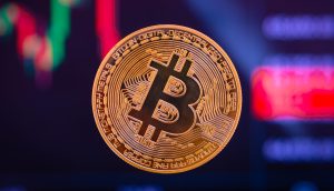 Nahaufnahme einer Bitcoin Münze vor dem Chart von Bitcoin