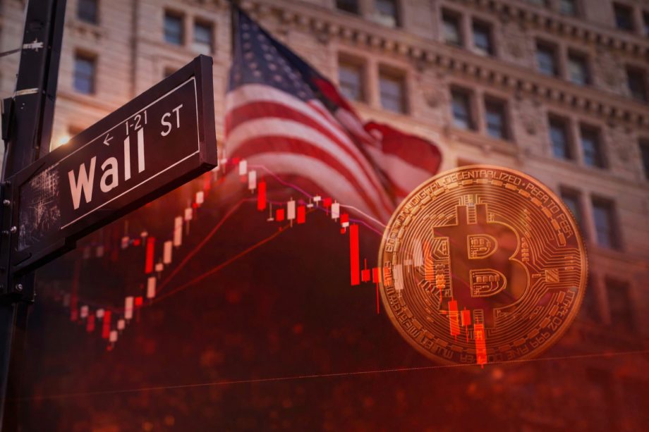 Das Bild zeigt einen nach unten gerichteten Kurs-Chart im Vordergrund. Im Hintergrund sieht man ein Straßenschild der Wall Street, eine US-Flagge und eine Bitcoin-Münze.