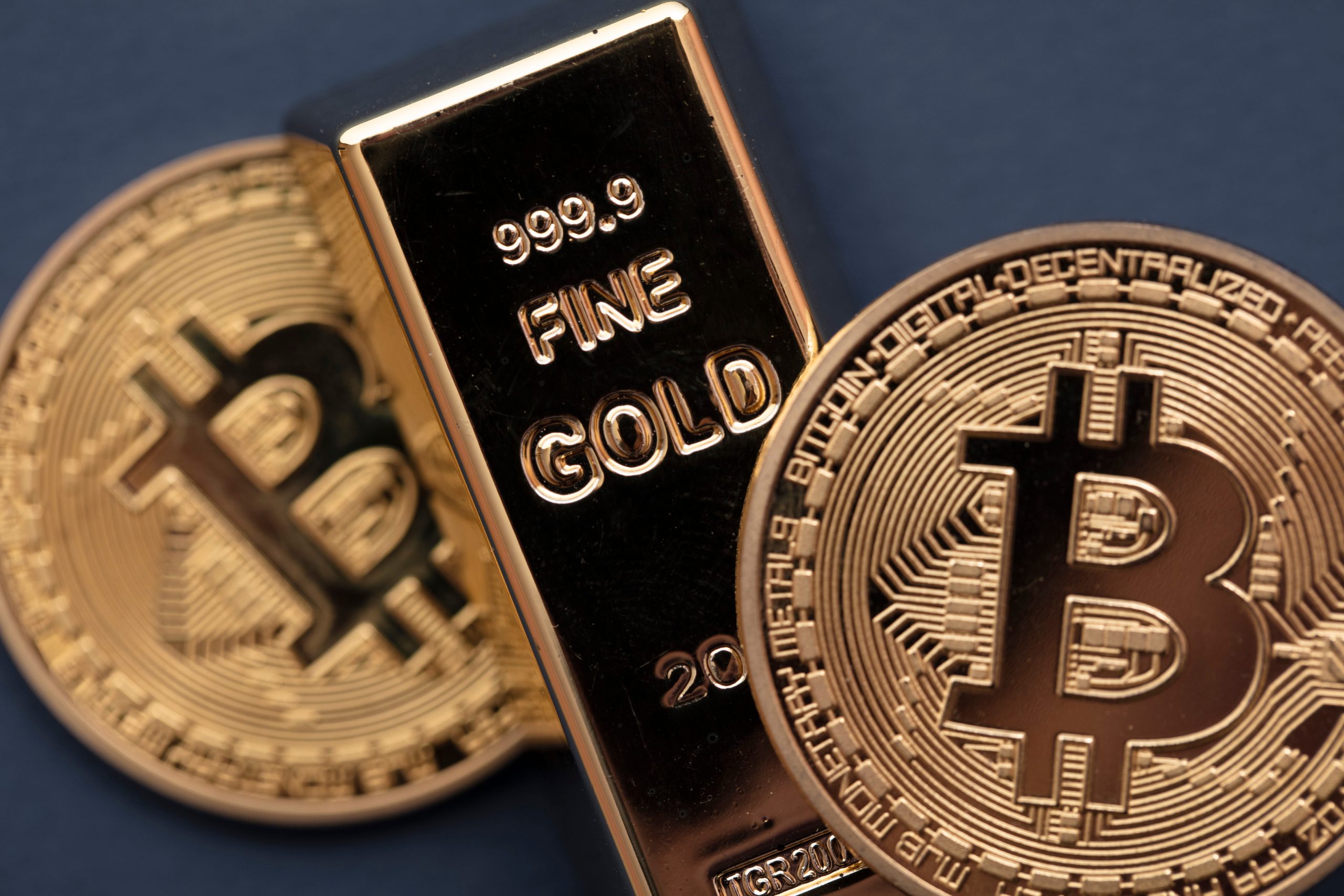 Eine Bitcoin-Münze liegt neben einem Goldbarren