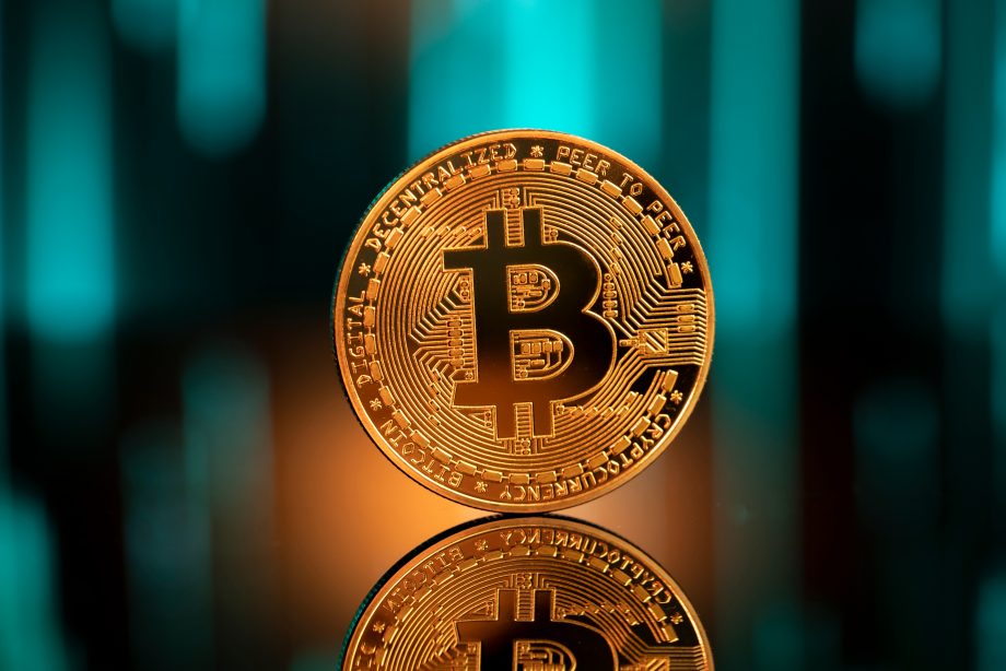 Eine Bitcoin-Münze vor einem grünen Hintergrund