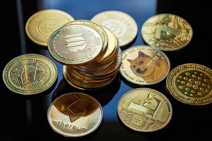 Eine Sammlung verschiedener physischer Altcoin-Kryptowährungsmünzen, darunter Ethereum, Solana, Dogecoin und Cardano, die auf einer reflektierenden schwarzen Oberfläche angezeigt werden.