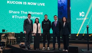 Menschen stehen auf Bühne bei Krypto-Konferenz von KuCoin