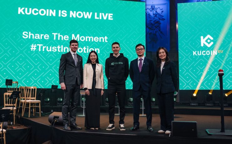 Menschen stehen auf Bühne bei Krypto-Konferenz von KuCoin