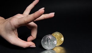 Eine Hand flippt eine Bitcoin-Münze vor einem schwarzen Hintergrund
