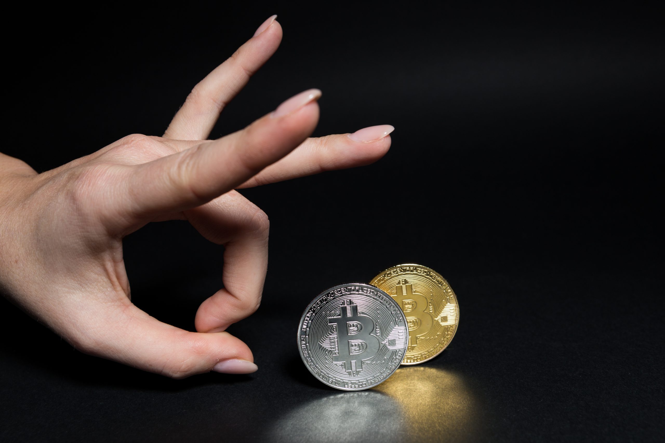 Eine Hand flippt eine Bitcoin-Münze vor einem schwarzen Hintergrund