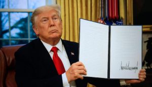 Donald Trump hält ein unterzeichnetes Gesetz in die Kamera