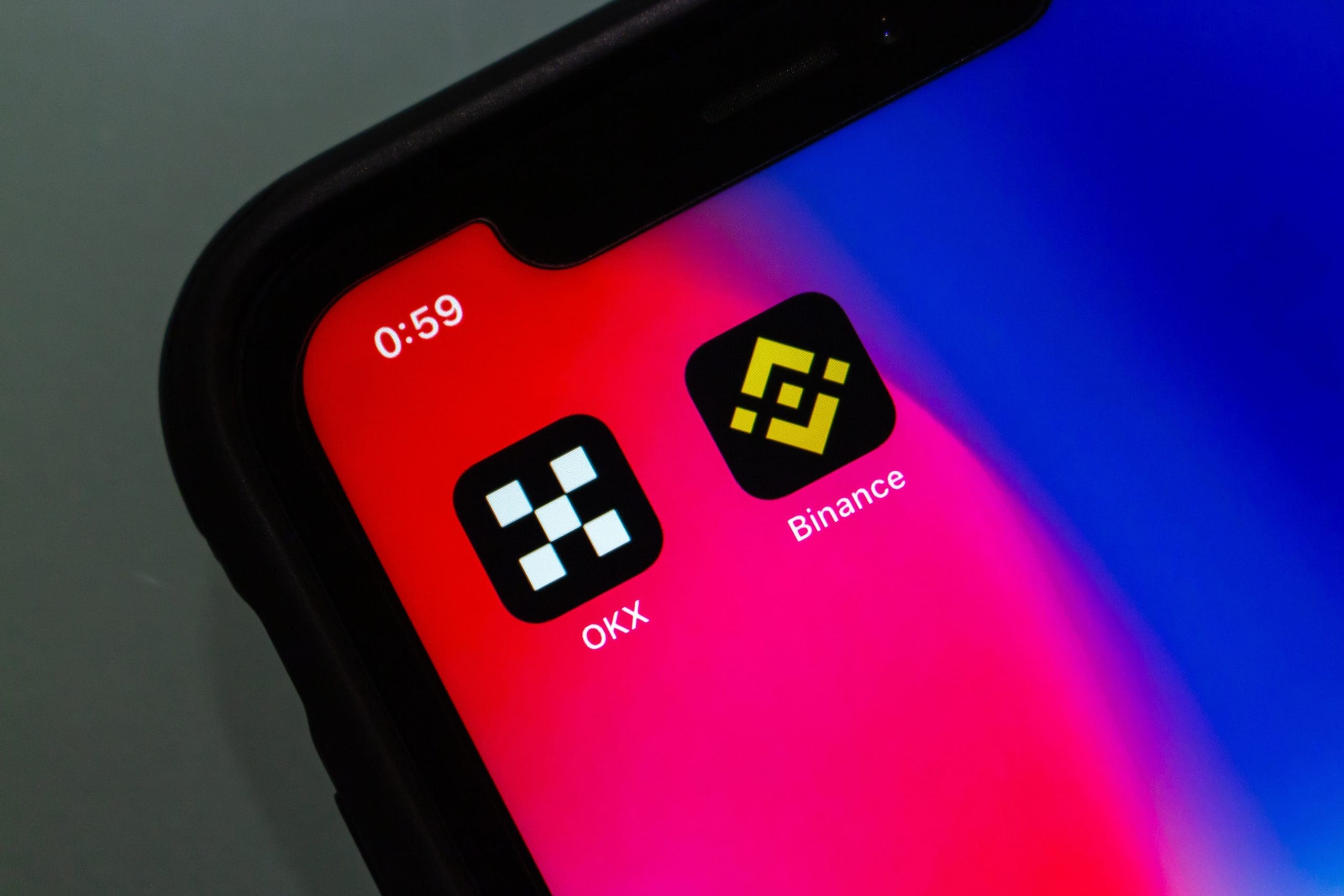 Auf einem Smartphone sieht man die App von OKX neben der Binance App.