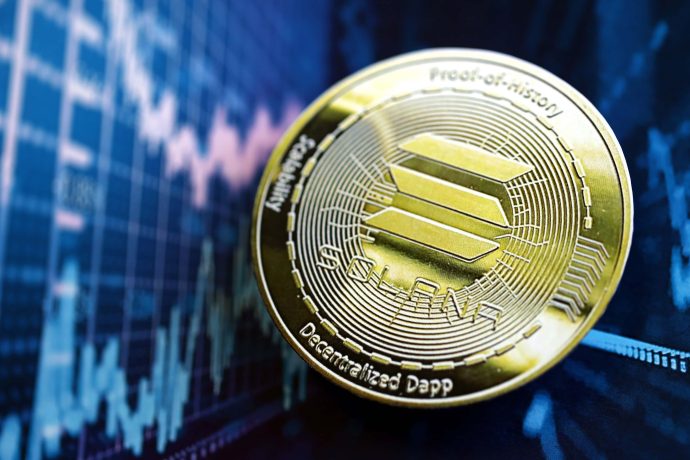 Eine glänzende Solana-Kryptowährungsmünze ruht auf einer Oberfläche, mit einer unscharfen Finanzgrafik im Hintergrund.