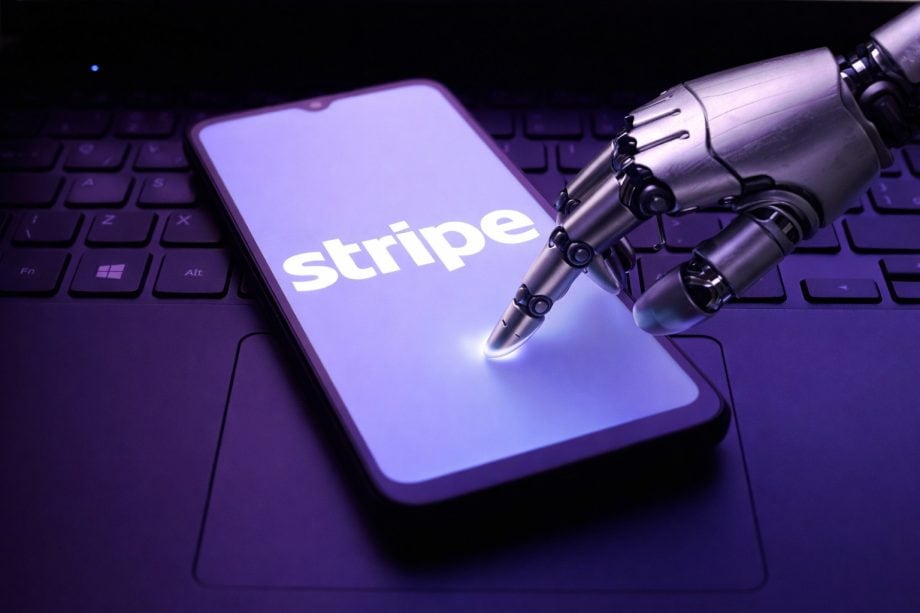 Eine Roboterhand berührt ein Smartphone, das das Logo von Stripe abbildet