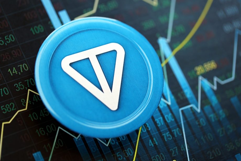 Eine Münze mit Toncoin-Logo liegt auf einem blau gefärbten Kurschart