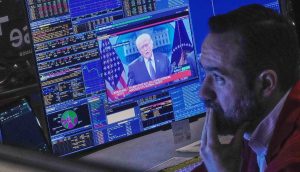 Trader blickt besorgt auf Bildschirm mit Donald Trump
