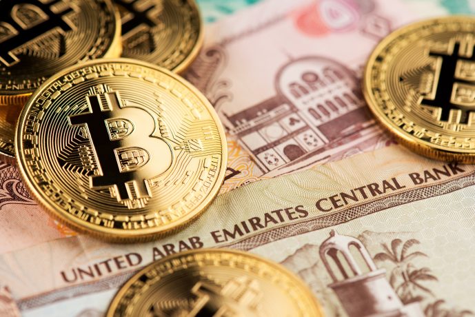 Bitcoin-Münzen neben Dirham-Scheinen