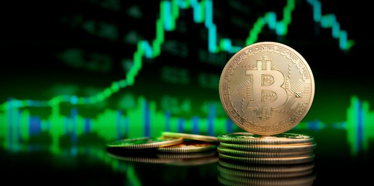 Eine Bitcoin-Münze vor einem grünen Chartdiagramm.