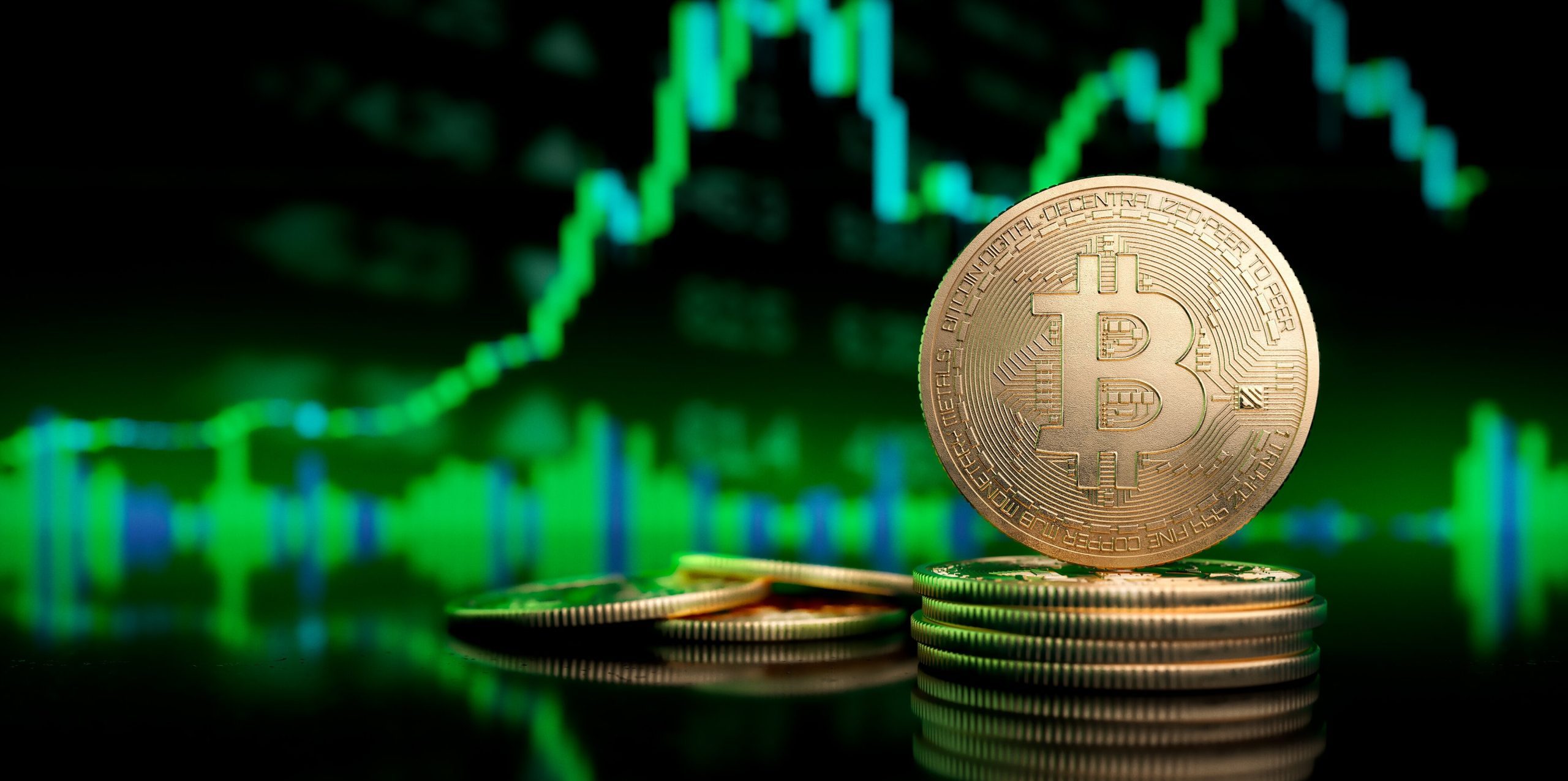 Eine Bitcoin-Münze vor einem grünen Chartdiagramm.