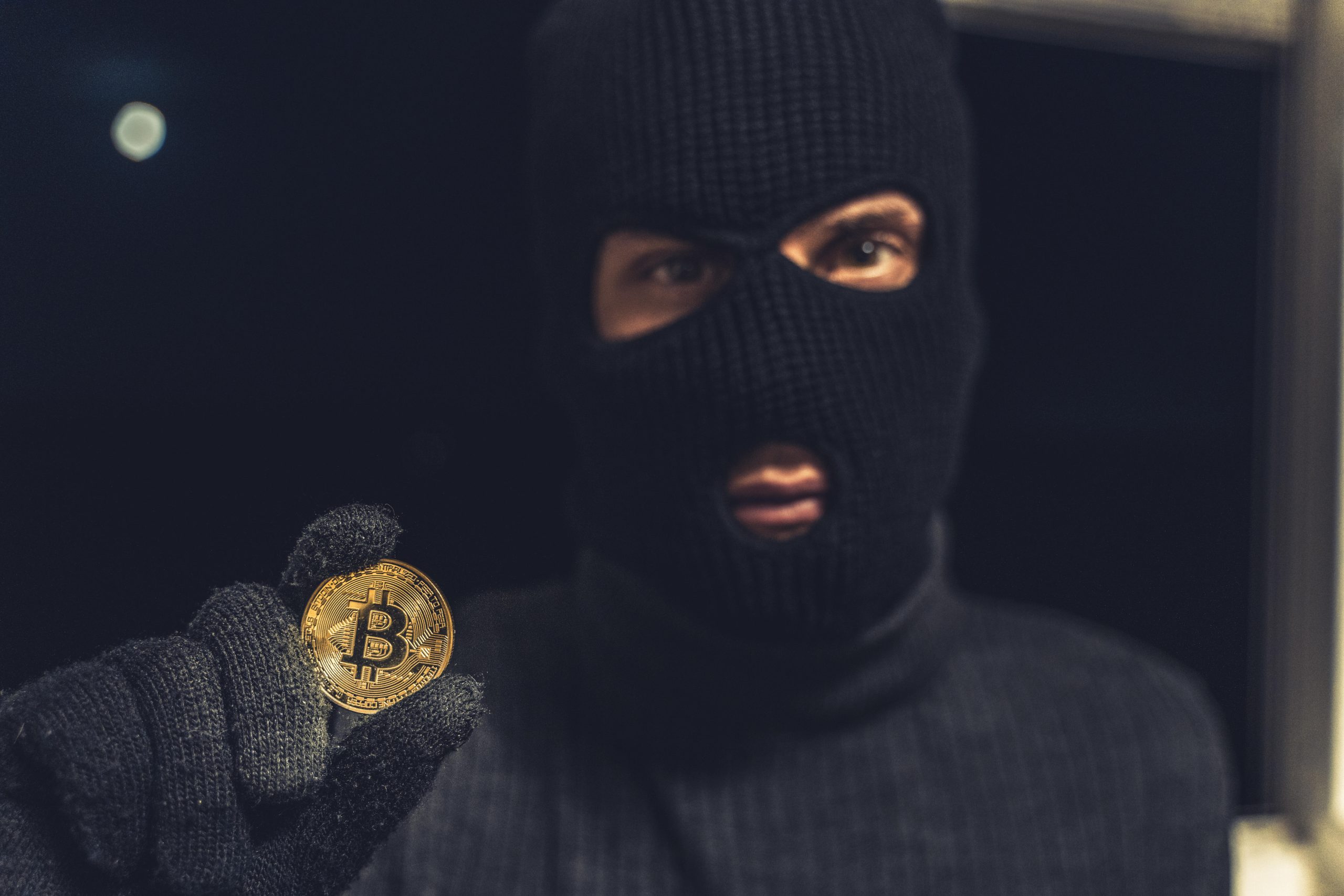 Das Bild zeigt einen Mann mit einer Bitcoin-Münze in der Hand