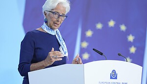 Eine Frau mit kurzen weißen Haaren und Brille (Christine Lagarde) spricht an einem Podium mit der Aufschrift Europäische Zentralbank Eurosystem, im Hintergrund ist eine EU-Flagge zu sehen.
