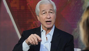 Ein grauhaariger Mann im Anzug zeigt mit dem Zeigefinger auf etwas.