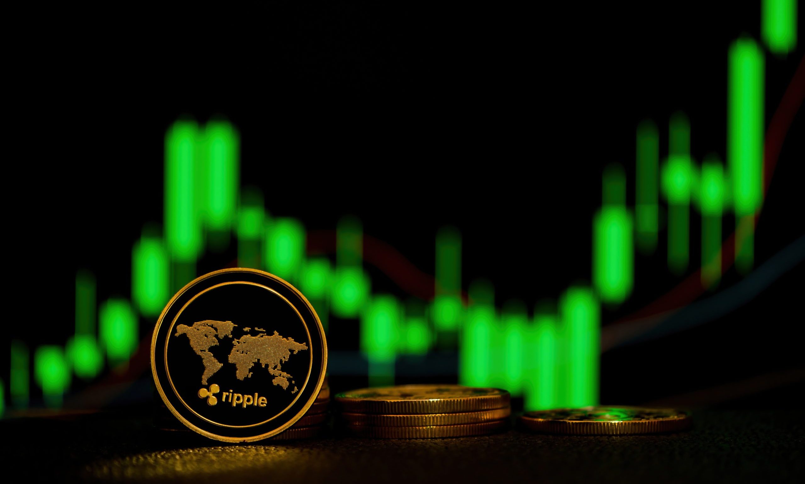 Eine Ripple XRP-Kryptowährungsmünze, die aufrecht vor gestapelten Münzen steht, mit einem grünen Candlestick-Kursdiagramm im unscharfen Hintergrund.