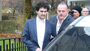 Sam Bankman-Fried steigt in ein Auto. Neben ihm ein Polizist.