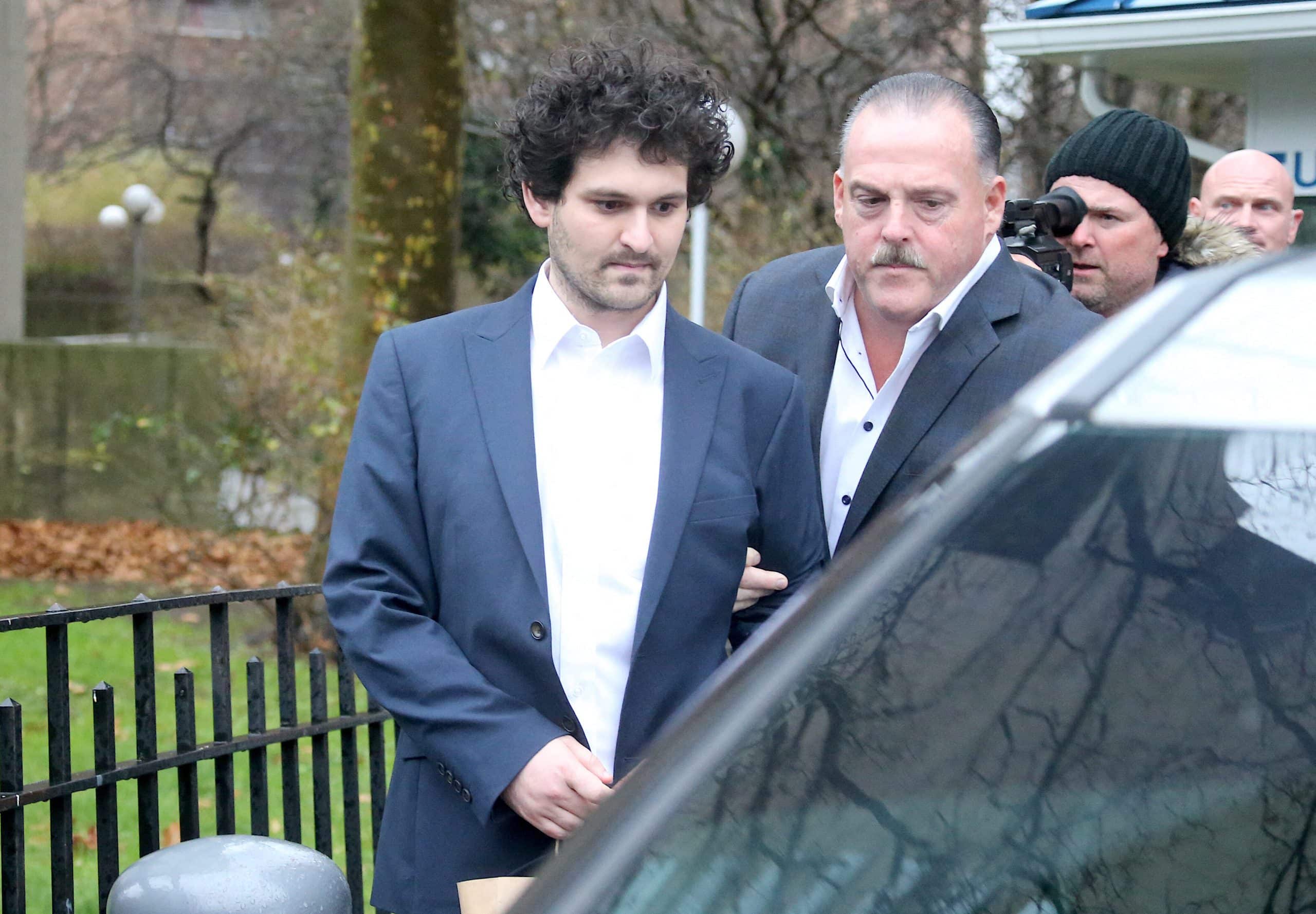 Sam Bankman-Fried steigt in ein Auto. Neben ihm ein Polizist.